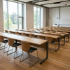 Modern wood-finish university student desks and chairs in a bright, sunlit tiered lecture hall