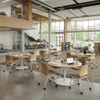 Minimalist circular discussion tables with star-base metal legs placed in a contemporary higher education student hub