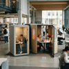 Group study pod with orange seating and large display screen, situated next to a single soundproof booth in a library