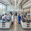 Large-scale central island benches with multi-tier storage shelves and steel frames in a professional education research lab