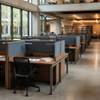 A well-lit, modern library study space furnished with acoustic modular study desks featuring warm integrated LED task lights. Each wood-grain carrel has a grey acoustic privacy panel, an ergonomic chair, and study materials, with book stacks visible in the background.