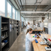 Tall steel chemical storage cabinet with glass doors in an active university research laboratory